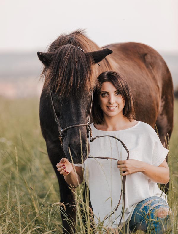 Pferdeosteopathin Isabella Caravetta mit Pferd im hohen Gras